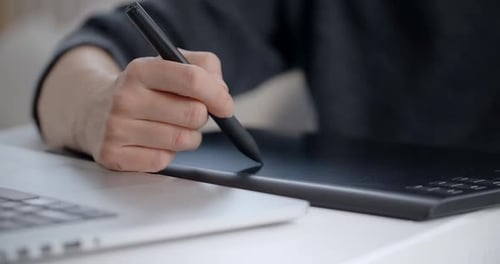 Hand Using Stylus on Graphics Tablet with Laptop