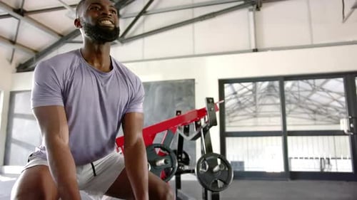 Using battle ropes, african american man exercising intensely in gym for strength training