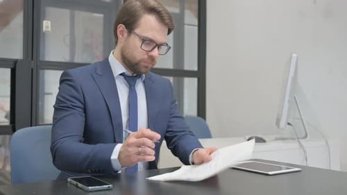 Businessman Reviews Documents in Office Workplace
