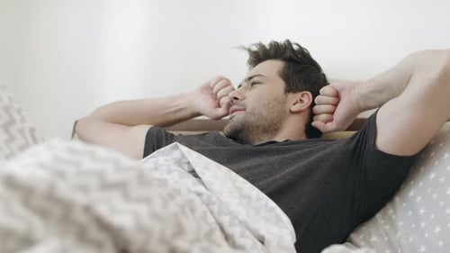 Man Stretching and Relaxing in Bed After Waking