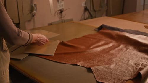 Person Cutting Leather with a Pattern at a Table