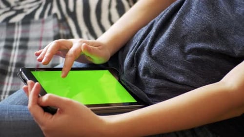 Young Woman Lying on Bed and Using Tablet with Green Screen at Home