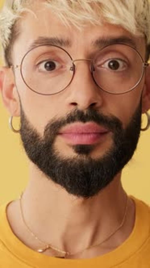 Close-up of amazed men looking at camera expressing wow isolated on yellow background in studio