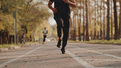 Young Muscular Athlete Running in the Alley of a City Park with Gradual Acceleration Concept of