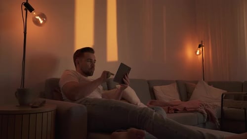 Man Relaxing on Sofa Using Tablet at Home
