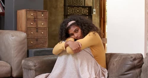 Cozy at home, woman comforting friend on couch with warm blanket