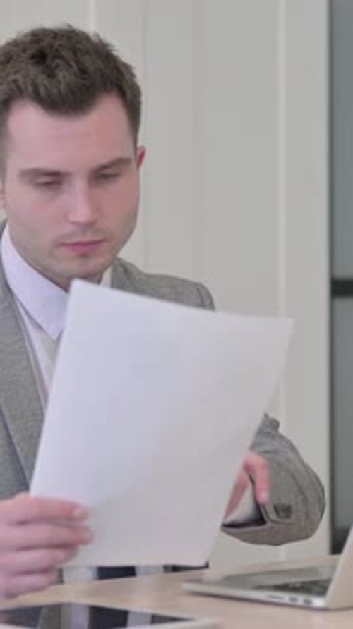 Man in Suit Reviews Document With Positive Reaction