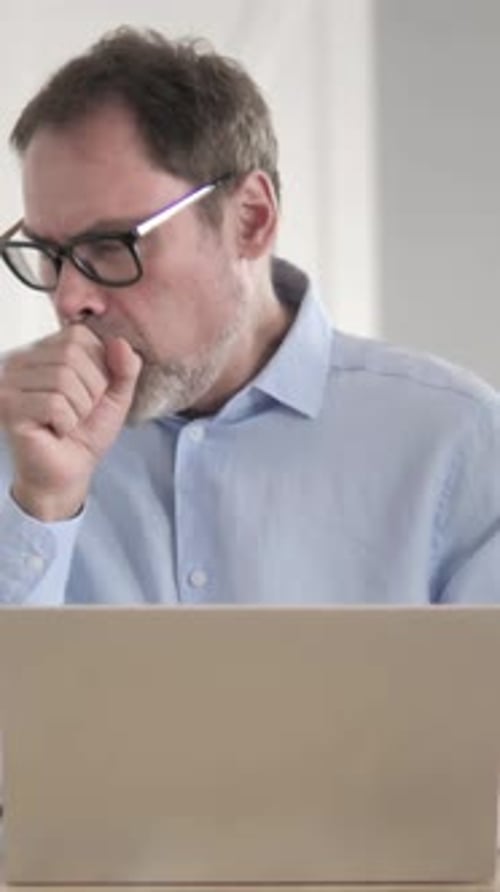 Man Coughing While Using Laptop Inside Home