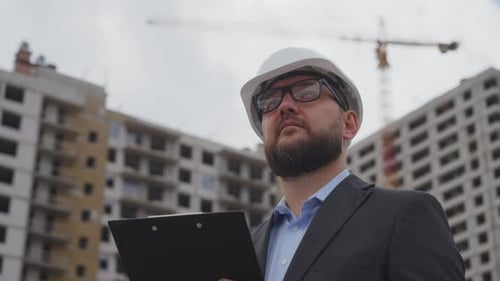 Bärtiger Bauingenieur macht sich Notizen auf der Baustelle