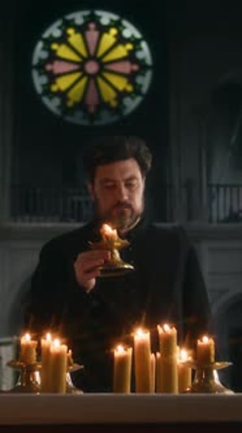 Vertical of Priest Putting Candle on Altar Praying in Catholic Church