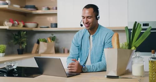Hombre con auriculares que usa una computadora portátil y con una sonrisa se comunica a través de un chat de Vídeo.