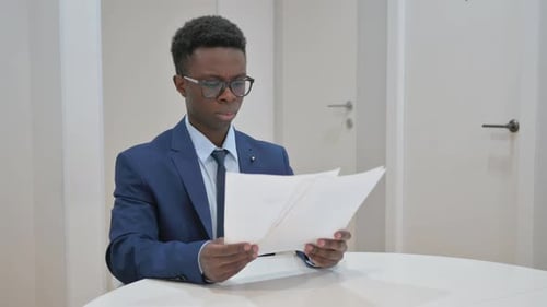 African Businessman Reviewing Documents in Office