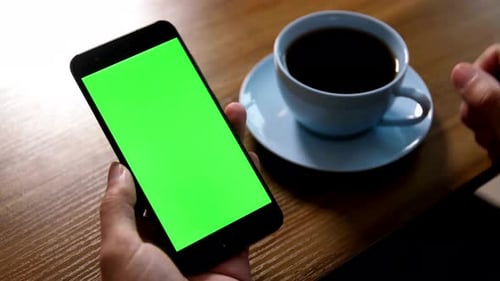 Hand Using Smartphone with Green Screen at Cafe