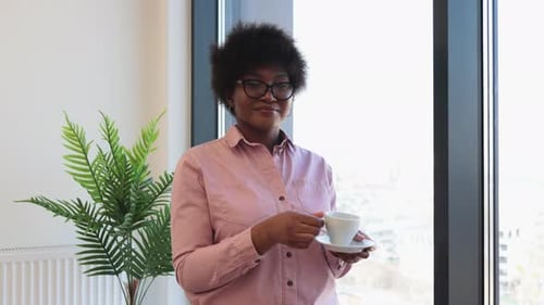Woman Holding Cup by a Bright Window Indoors