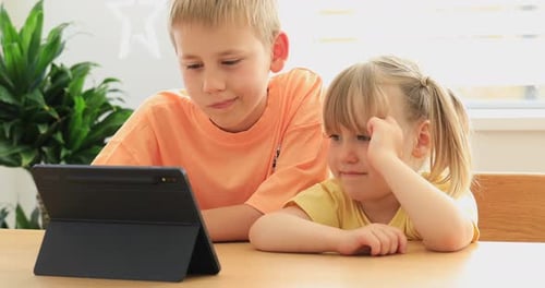 Boy and Girl Watch Tablet at Table