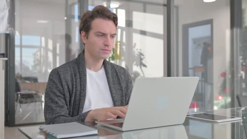 Young Man Working on Laptop in Office