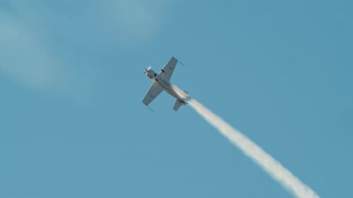 Aerobatic Airplane Flying and Smoke in Blue Sky