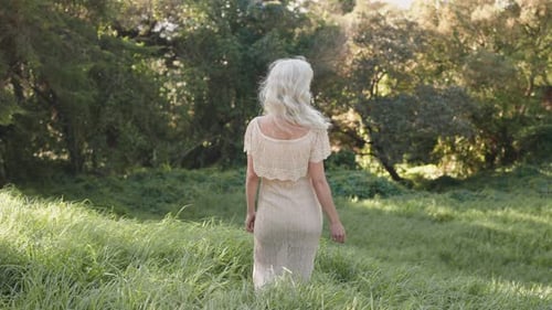 Beautiful Woman in White Dress Walking Through a Sunny Field in Nature