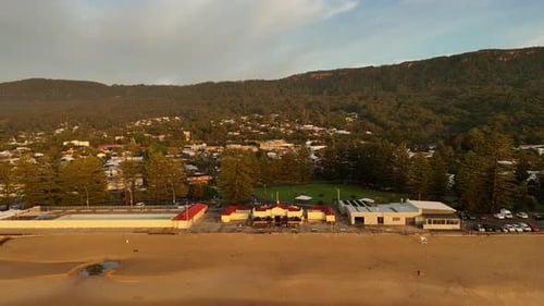 Aerial Pullback Over Thirroul Surf Club With Sand and Waves in Sunny Conditions