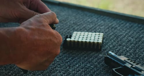Adult Hands Loading Bullets into Magazine at Range