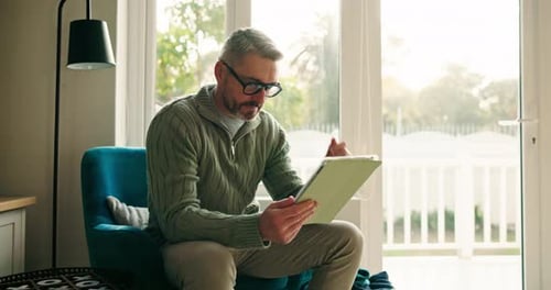 Man Using Tablet Device While Relaxing in Chair