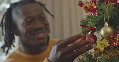 Man Decorating Christmas Tree with Ornaments at Home