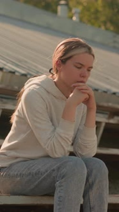Reflective Woman Sitting on Rustic Stadium Bleachers