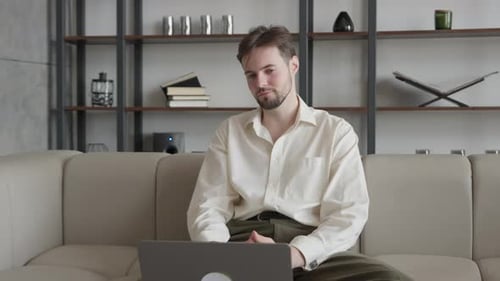 Man On Video Call Shaking Head In Disagreement While Sitting On Sofa At Home