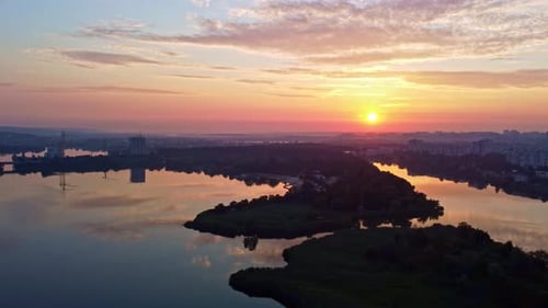 Aerial track footage of sunrise on lake in city
