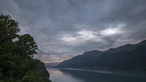 Zeitraffer von Sonnenuntergangswolken über einem Schweizer Alpensee. Die Wolken rollen auf die Kamera zu, wenn sie sich drehen