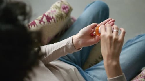 Woman Pours Pills Into Hand From Bottle