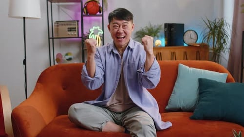 Man Celebrates Good News on a Couch Indoors