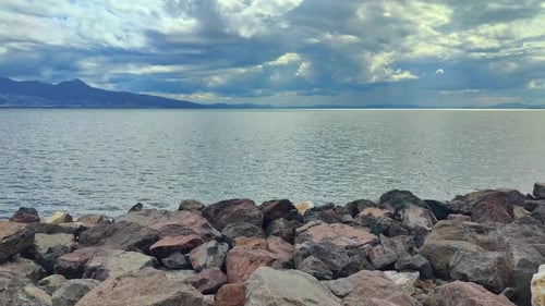 Cloudy Sky Shines above the Waves Gently Lapping the Rocky Shore