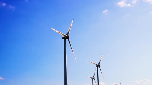 Wind turbines producing energy. Wind turbines stand tall against a clear blue sky