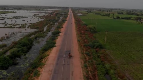 Aerial drone shot over main highway with left side of agricultural land submerged by severe river fl