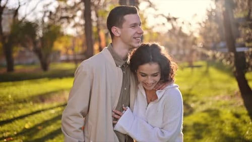 A romantic couple in an autumn park. Walking along the path hugging each other. Autumn atmosphere, y