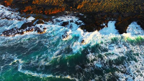 Top Down View on Ocean Waves Crashing and Foaming Around Majestic Rocks and Cliffs Inspiring and