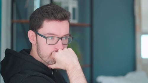 Pensive young man sitting pondering in living room. deep thought considering problems solving, havin