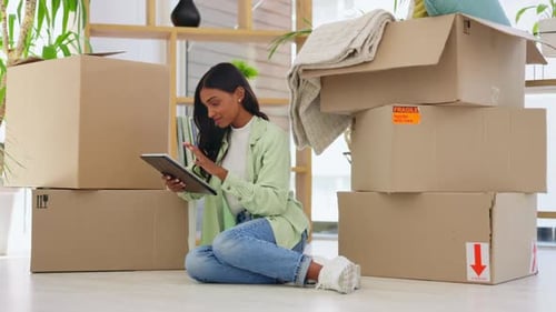 Woman Using Tablet Surrounded by Moving Boxes