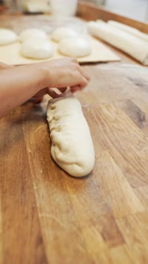 The Baker is Molding Bread From the Dough in the Bakery