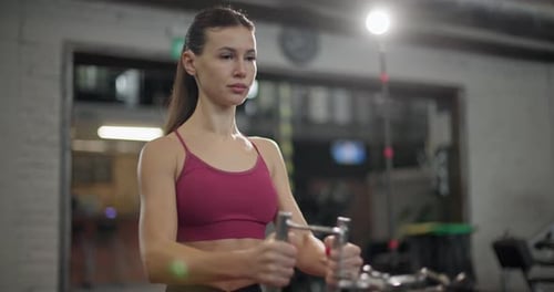 A Young Beautiful Brunette Girl in Sportswear is Exercising on a Machine in the Gym Doing Exercises