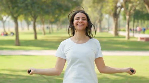 Happy Woman Jumping Rope for Fitness in Park