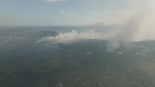 Wide drone shot of a forest fire on an island.