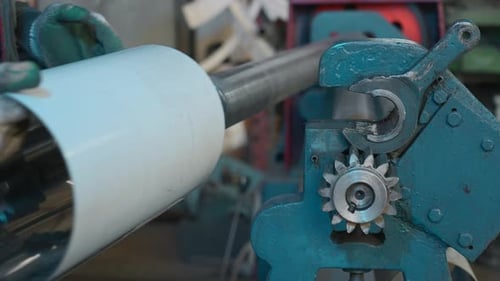 Worker at a factory by a metal rolling machine bending a steel sheet