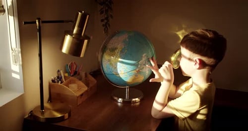 Boy Exploring Globe with Magnifying Glass at Desk