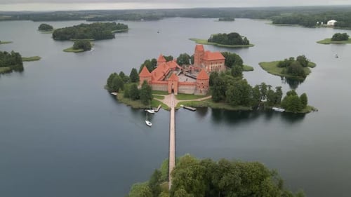 Aerial shot of the Trakai castle surrounded by trees over the Galves lake in Trakai, Lithuania