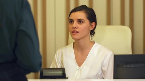 Woman at Reception Desk Receives Paperwork