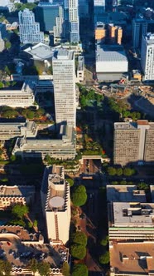 Rising above sunlit Los Angeles downtown. Crazy traffic on the roads of metropolis from aerial view