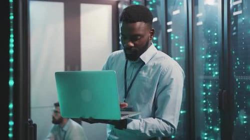 Man Working on Laptop in Server Room