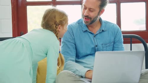 Atractivo padre caucásico usando una computadora portátil con su hija pequeña.